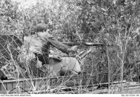 312601 Lance Corporal (L/Cpl) Leonard (Len) Ellcombe of Heidelberg, Vic, standing on an Armoured Personnel Carrier (APC), blazes away with an M60 machine gun at a Viet Cong (VC) rocket launcher crew that attempted to ambush the APCs. Also identified, (second from left), is 312641 Private (Pte) Brian \\'Jock\\' Rennie. L/Cpl Ellcombe was with a section of the 1st Australian Task Force (1ATF) Defence and Employment platoon which was attached to 2 Troop of B Squadron, 3rd Cavalry Regiment during a sw