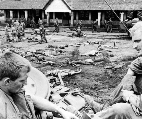The bodies of North Vietnamese Army troops who attempted to hold the rubber plantation village of Binh Ba, are laid out in an open area so they can be checked for documents before burial. In the foreground are some of the Australian troops who fought in the battle, June 1969.