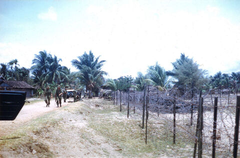 Lt. A.E. (Ted) Pott and Corporal Bobby Harboard walking south out of Xa Phuoc Loi on Route 44. The Australian Engineers had advised us that the barbed wire fence next to Route 44 had been booby trapped by the V.C.. 9.4.1967
